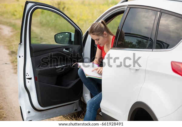 Beautiful young woman got lost while driving\
car at countryside