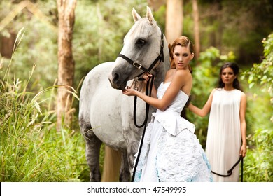beautiful young woman with a grey horse in the rainforest