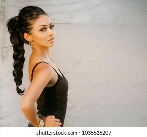 Beautiful young woman hair pulled back stylishly posing outdoors in urban city setting.