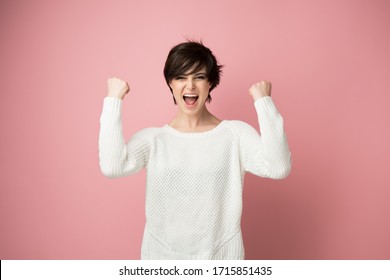Schöne junge Frau glücklich und aufgeregt ausdrücken Siegergeste. Erfolgreiches hübsches Mädchen, das den Sieg feiert, triumphiert, Studioaufnahme auf rosafarbenem Hintergrund