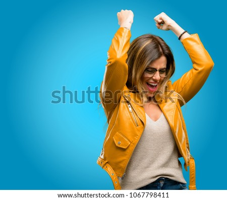 Beautiful young woman happy and excited expressing winning gesture. Successful and celebrating victory, triumphant, blue background