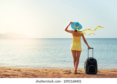 Beautiful young woman with a hat standing with suitcase on the wonderful sea background, concept of time to travel, with space for your text. - Powered by Shutterstock