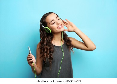 Beautiful young woman in headphones listening to music on light background - Powered by Shutterstock