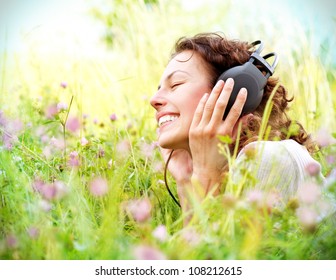 Beautiful Young Woman with Headphones Outdoors. Enjoying Music - Powered by Shutterstock