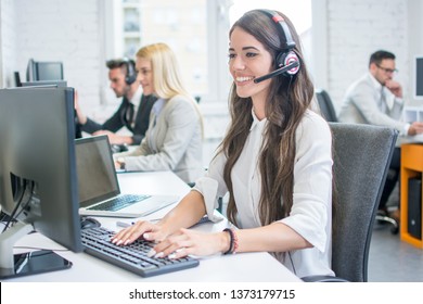 Beautiful Young Woman With Headset Working On Computer While Talking With Client In Call Center. Online Customer Support.