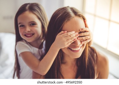 Beautiful Young Woman And Her Charming Little Daughter Are Hugging, Looking At Camera And Smiling