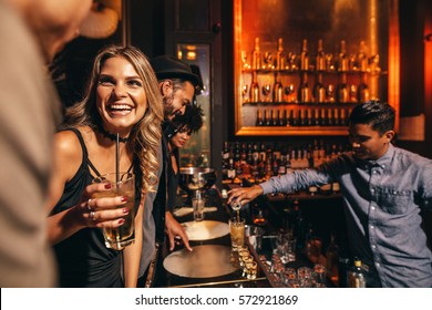 Beautiful Young Woman With Her Friends At Bar. Young People Enjoying A Night At Club.