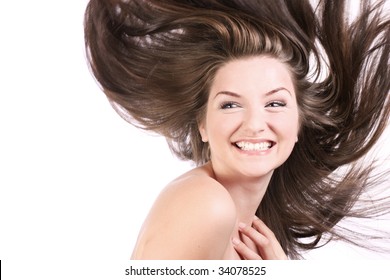 A beautiful young woman with her hair blowing and smiling, in front of a white background.