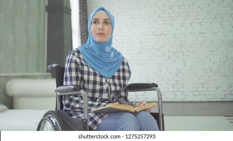 A beautiful young woman in a hijab is blind or weakly imposing, a wheelchair reading a braille font. - Powered by Shutterstock