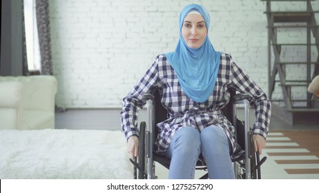 beautiful young woman in hijab disabled person, wheelchair, in apartment