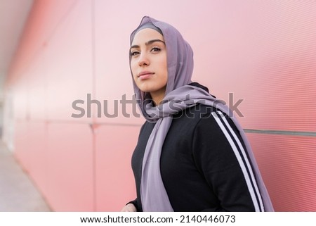 Beautiful young woman in hijab and sportswear on the street looking at horizon - arab sportswoman concept -