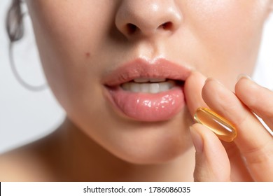 Beautiful Young Woman Hold Vitamin Fish Oil Capsule Omega-3 Pill In Hand Near Open Mouth Closeup. Food Beauty Supplements, Diet Nutrition, Healthy Eating. Focus On The Pill.