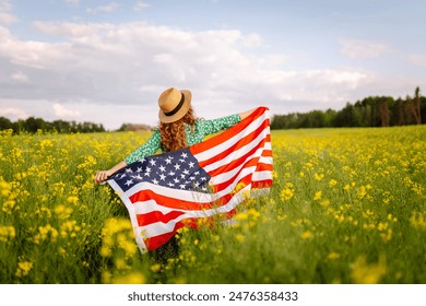 Beautiful young woman holding an American flag in the wind in a field. Patriotic holiday. USA celebrate 4th of July. - Powered by Shutterstock