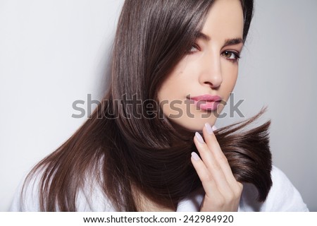 beautiful young woman holding her healthy and shiny hair, studio white