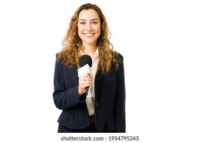 Beautiful young woman holding a microphone and smiling. Female latin journalist ready to do a live report on the tv news against a white background