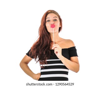 Beautiful Young Woman Holding A Photo Booth Prop In The Shape Of Red Lips Against A White Background