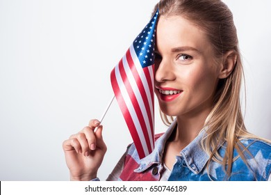 Beautiful Young Woman Holding Small American Flag And Smiling At Camera