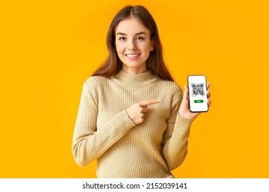 Beautiful young woman holding smartphone with QR code on screen against orange background - Powered by Shutterstock