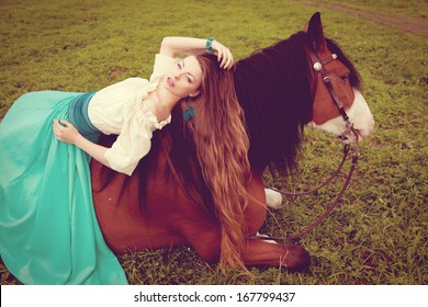 Beautiful young woman with a horse in the field. Girl on a farm with animal. Luxury woman outdoors
