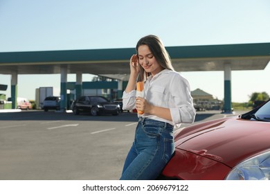 Beautiful Young Woman With Hot Dog Near Car At Gas Station. Space For Text