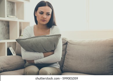 Beautiful Young Woman Is Hugging A Cushion While Sitting Sadly On The Couch At The Psychologist