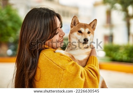 Beautiful young woman hugging happy shiba inu dog at park
