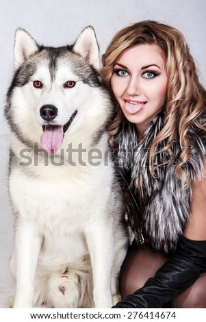 Beautiful young woman with a husky dog over grey background