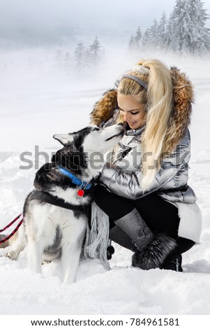 Beautiful young woman with Husky dog. Winter fashion. Snow, mountains and winter vacations.