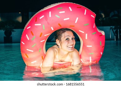 Beautiful Young Woman With Inflatable Ring In Hotel Pool At Night