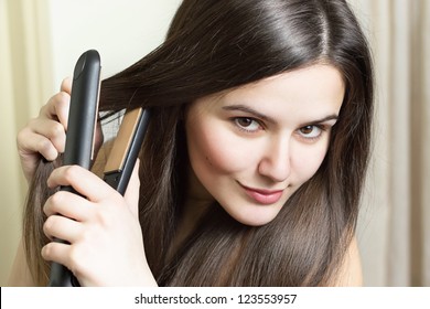 Beautiful Young Woman Ironing Her Hair