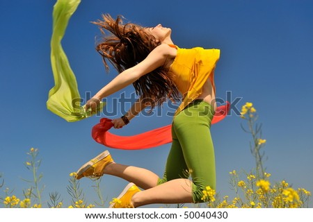 beautiful young woman jumping on field in summer