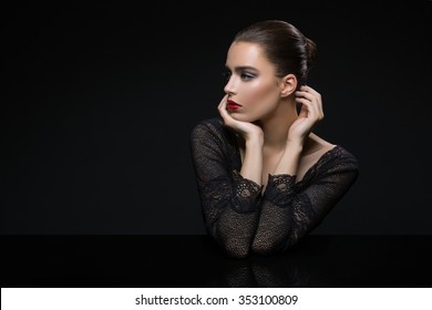 Beautiful Young Woman In Lace Top With Red Lips Touching Face. Over Black Background. Copy Space.