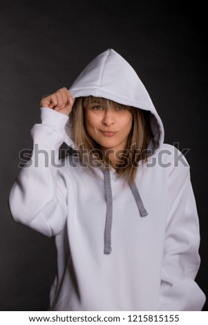 Beautiful young woman in a large white hooded sweatshirt. Studio portrait on black background