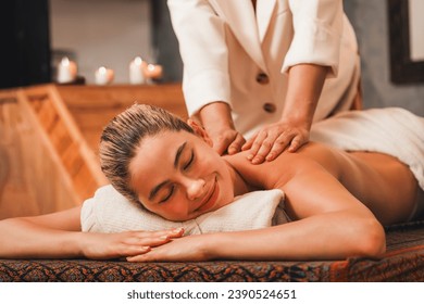 Beautiful young woman lies on spa bed in front of wooden sauna cabinet during having back massage. Attractive women in white towel in warm sauna room. Relaxing and healthy concept Tranquility. - Powered by Shutterstock