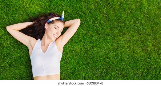 Beautiful young woman lies on the grass. Fresh natural summer concept. View from the top.