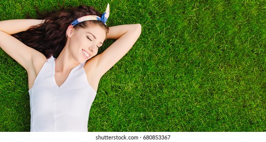 Beautiful young woman lies on the grass. Fresh natural summer concept. View from the top.
