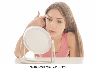 beautiful young woman lifting her eyebrows in front of a mirror