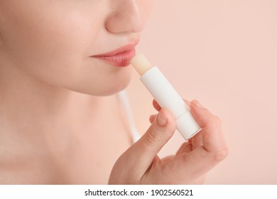 Beautiful young woman with lip balm on color background, closeup - Shutterstock ID 1902560521