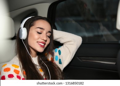 Beautiful Young Woman Listening To Music With Headphones In Car. Space For Text