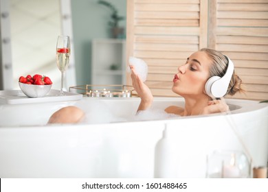 Beautiful young woman listening to music in bathroom - Powered by Shutterstock