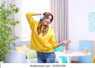 Beautiful young woman listening to music in headphones at home - Powered by Shutterstock