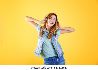 Beautiful young woman listening to music in headphones on color background - Powered by Shutterstock