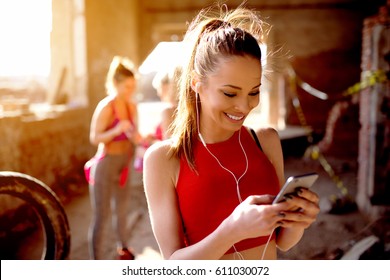 Beautiful Young Woman Listening Music Fitness Training Workout. Group Of Fitness People Behind Preparing For Training.