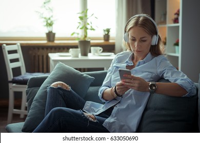 Beautiful young woman listening to the music on cozy sofa - Shutterstock ID 633050690
