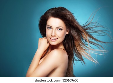 Beautiful Young Woman With Long Brown Flying Hair On  Blue Backg