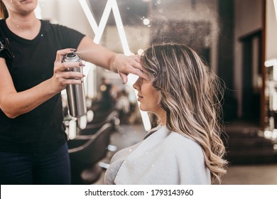 Beautiful young woman with long curly hair in hair salon. Professional hairdresser styling with hairspray. - Powered by Shutterstock