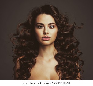 Beautiful young woman with long curly brown hair and  smoky eye makeup. Sexy and gorgeous brunette girl  with a wavy hairstyle. Portrait of an attractive female. Fashion model. 