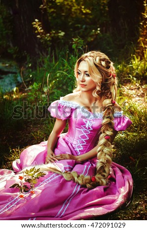 Beautiful young woman with long hair braided in a braid, sitting in the woods.