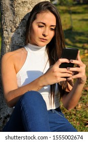 Beautiful Young Woman Looking At Cell Phone In Public Square