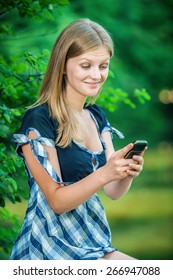 Beautiful young woman looking at mobile phone on green background - Shutterstock ID 266947088